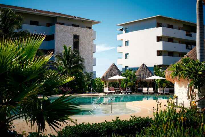 The white modern-style buildings and pools surrounded by palm trees at one of the best adults-only all-inclusive resorts in Cancun, the Secretes Playa Mujeres.
