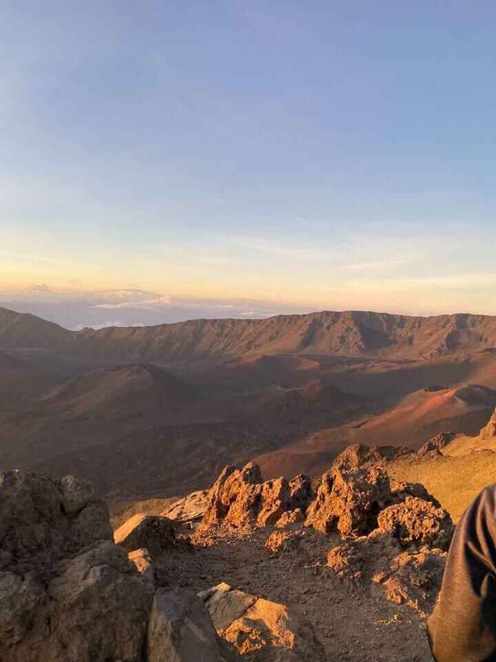 The view of the sunrise at Haleakala National Park overlooking volcanic craters and rugged rocky landscapes which is one of the cheap things to do in Maui, Hawaii.