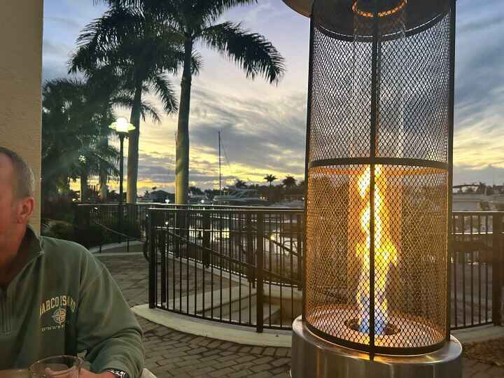 A warm sunset glow in the sky sitting outside on the patio for dinner near fire heaters while eating dinner at CJ's On the Bay restaurant in Marco Island.