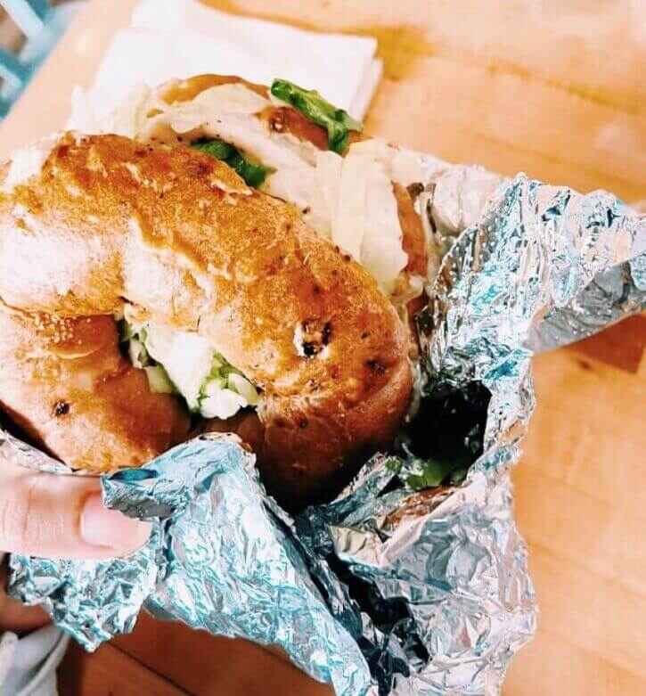 A yummy turkey bagel sandwich wrapped in tin foil from the Ripple Bagel Deli located in the Broad Ripple neighborhood of Indianapolis which is a popular breakfast spot.