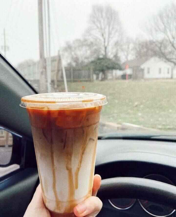 The aesthetic iced caramel macchiatto served at Mocha Nut Coffee Shop in Indianapolis on Southport Road viewed from a car on a rainy day.