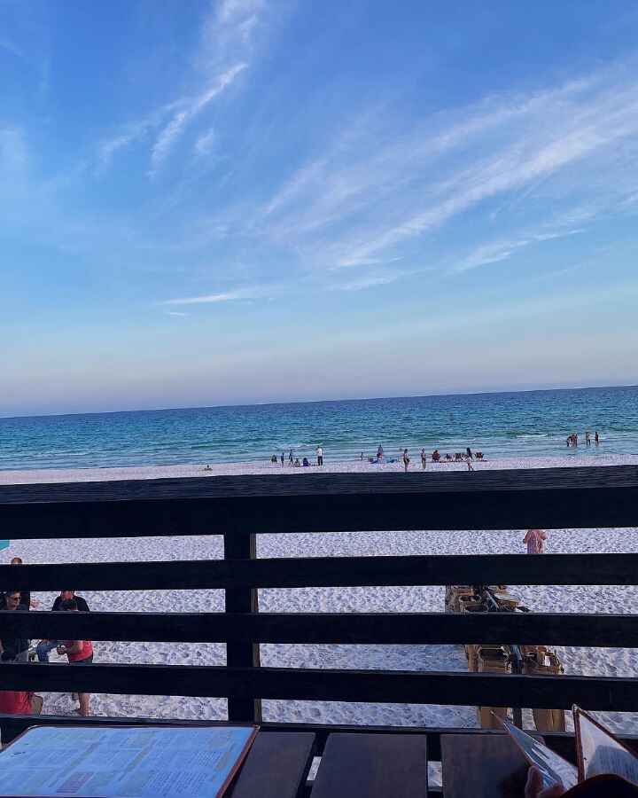 The view of the sunset over the emerald blue waters at the white sandy beach in Destin, Florida while enjoying dinner at the beachfront restaurant Pompano Joe's.