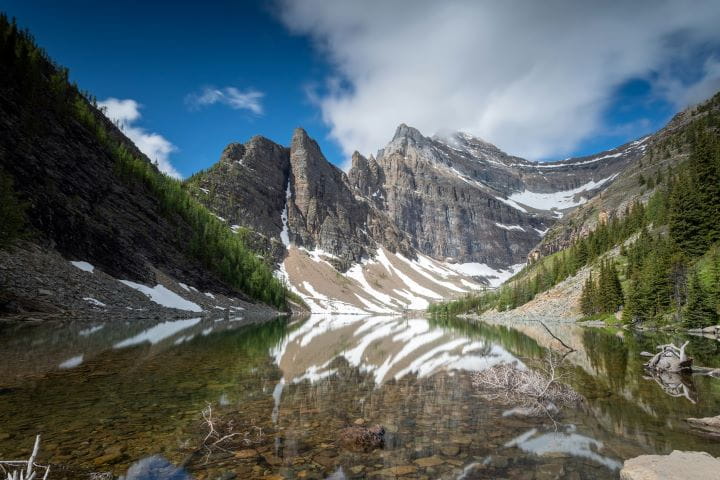 The clear reflections in the waters of Lake Agnes which is a smaller lake in Banff surrounded by mountains and trees and only accessible via a hiking trail to Lake Agnes Teahouse.