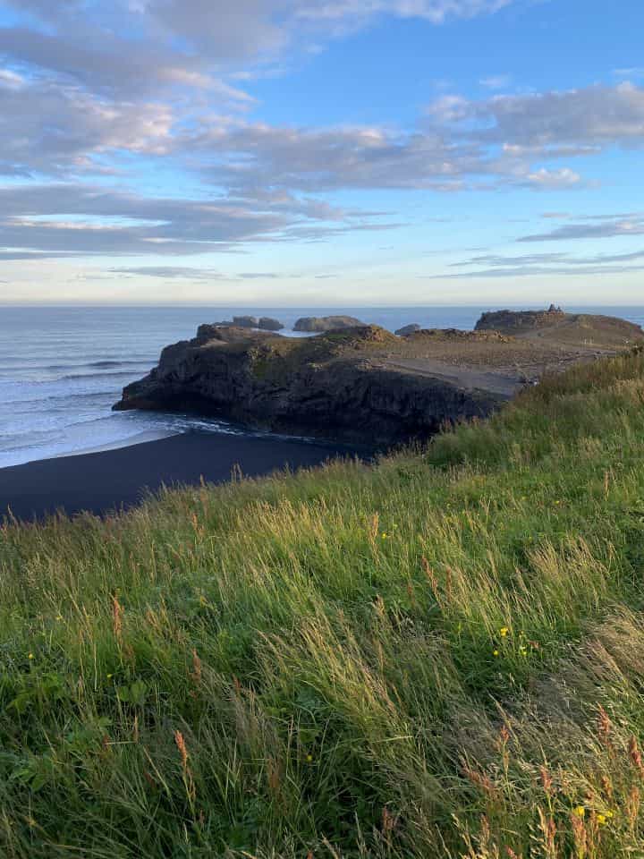 The view of the sunset near the Dyrhólaey Lighthouse with the view of the ocean and moss covered cliffs.