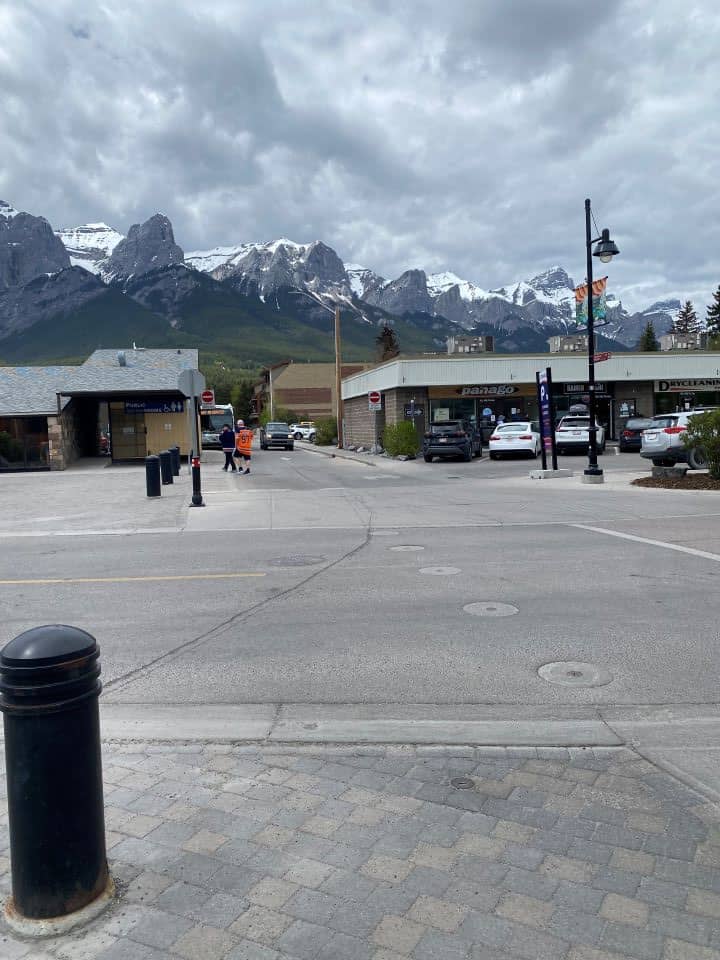 The view of the snow covered mountains you can see from downtown Canmore as you are walking along main street full of restaurants, shops, and cafes.