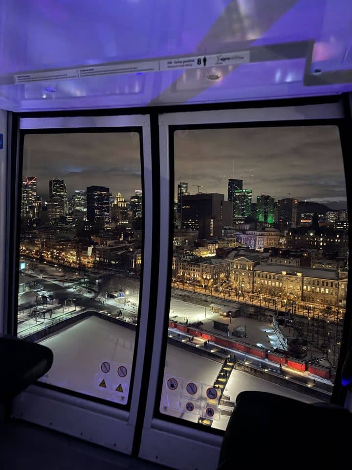 The view you can see while riding the Ferris wheel at the Old Port area in Montreal with the city skyline surrounding you being lit up at night.