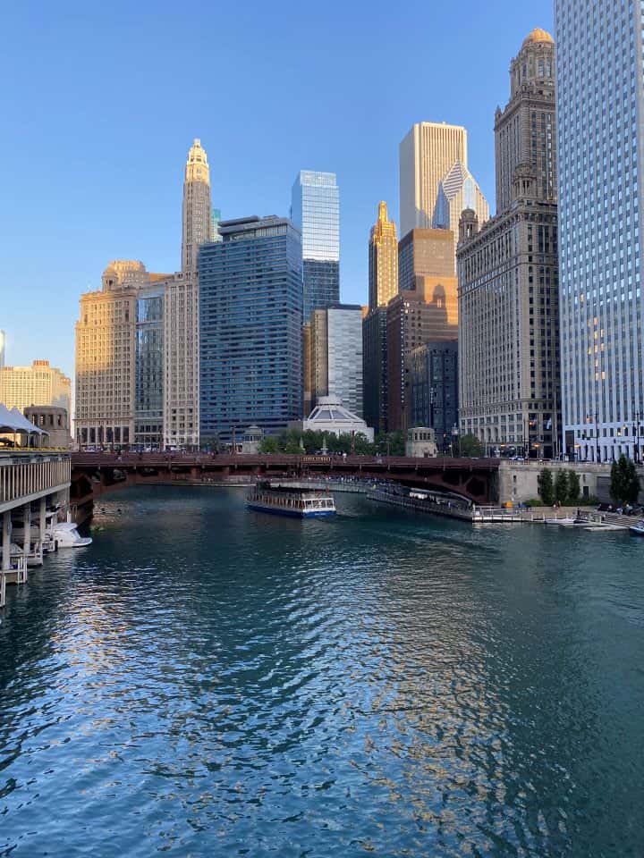 The beautiful tall buildings surrounding the Chicago River where you can walk over the bridge and along a path next to the River.