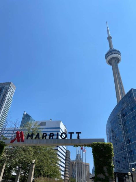 The tall CN Tower in the background behind the Marriott hotel in Toronto on a clear sunny day in the summer.