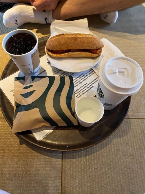 A black cold brew, cup of water, iced white chocolate mocha, and spicy chicken breakfast sandwich served at the Starbucks in Kyoto that is inside a a restored old town house where you can sit on tatami mats.