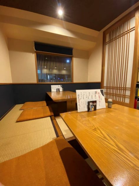 The traditional style interior of Wagyu Ramen Syomon in Kyoto with wooden tables and tatami mat flooring.