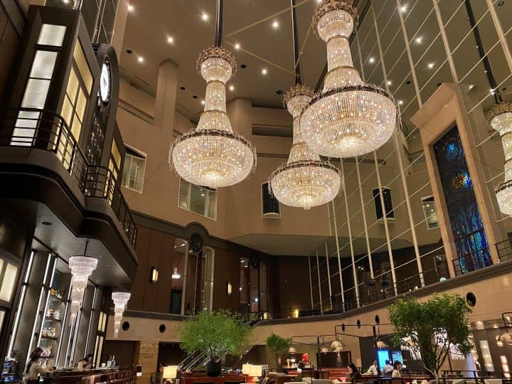 The beautifully decorated lobby in Hyatt Regency Tokyo with its large chandeliers and upscale dark wood bar.