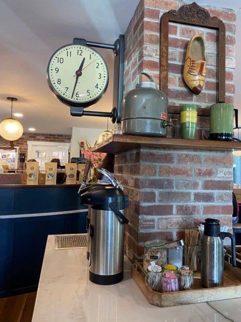 The cute interior of Kin Coffee and Crafthouse coffee shop in Holland, Michigan with its red brick column and old-fashioned school clock.