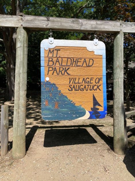 The large wooden sign marking the entrance of Mt. Baldhead Park in Saugatuck hanging on two wooden poles.