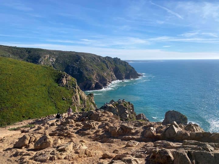 Panoramic view from a cliff at Cabo da Roca, featuring the vast ocean and steep cliffs under bright sunlight.