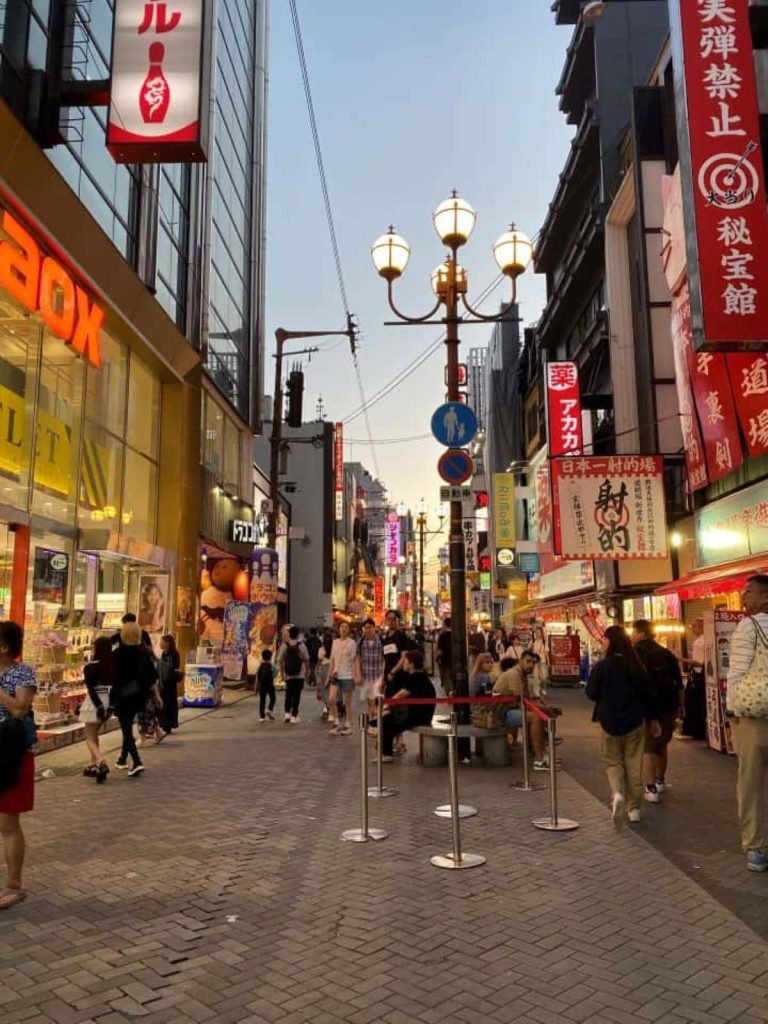 The lively scene at night in Dotonbori in Osaka with neon signs, bright lights, and food vendors lining the street, making it a must-visit on your 1-day Osaka itinerary.