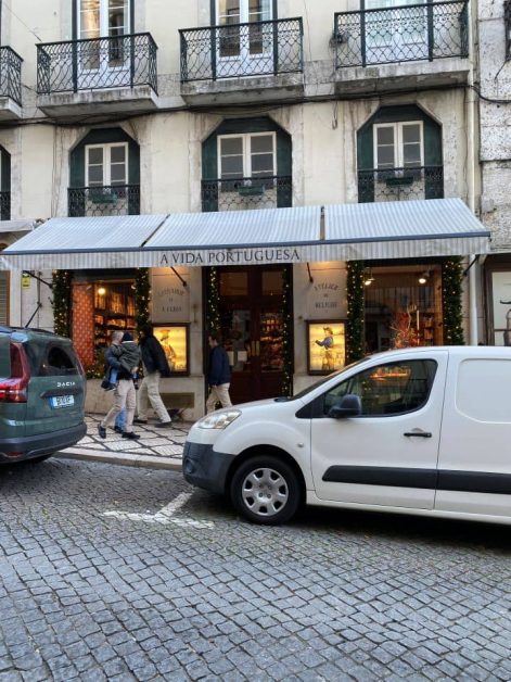 The outside of A Vida Portuguesa" home goods store in Lisbon with pedestrians passing by.