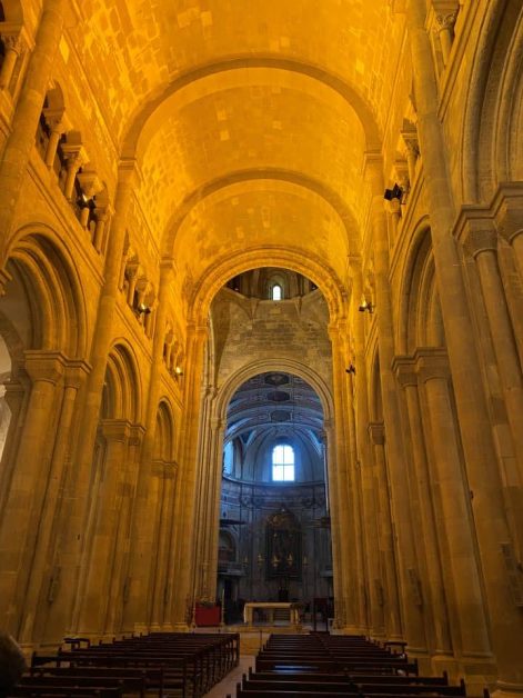 Interior of Lisbon Cathedral with high, arched ceilings glowing in warm golden light.