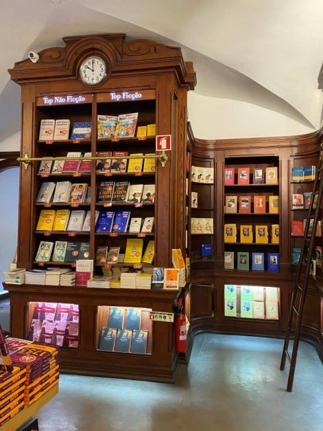 The inside of the world's oldest bookstore Livraria Bertrand featuring wooden shelves filled with colorful fiction and non-fiction books.