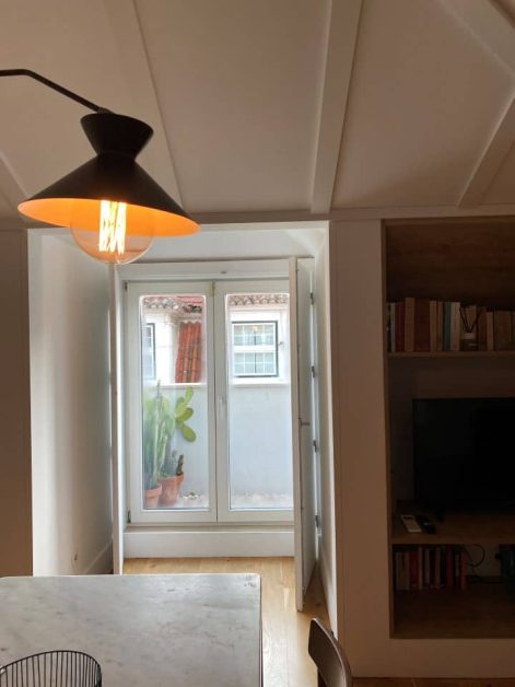 The warm light casting from the overhead lamp hanging over the dining table with the balcony door in the background at our 1-bedroom apartment stay at The Lisboans hotel.