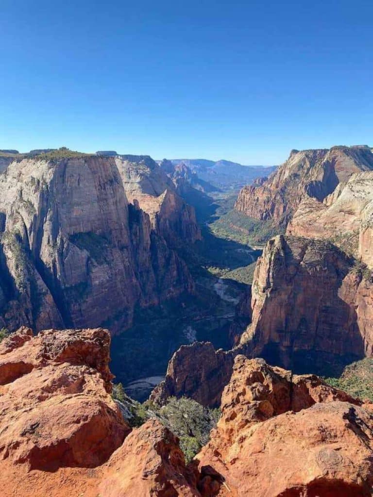 The stunning view from the top of Observation Point hike in Zion via the East Mesa Trail where you get sweeping views of Zion Canyon and a birds eye view of Angels Landing.