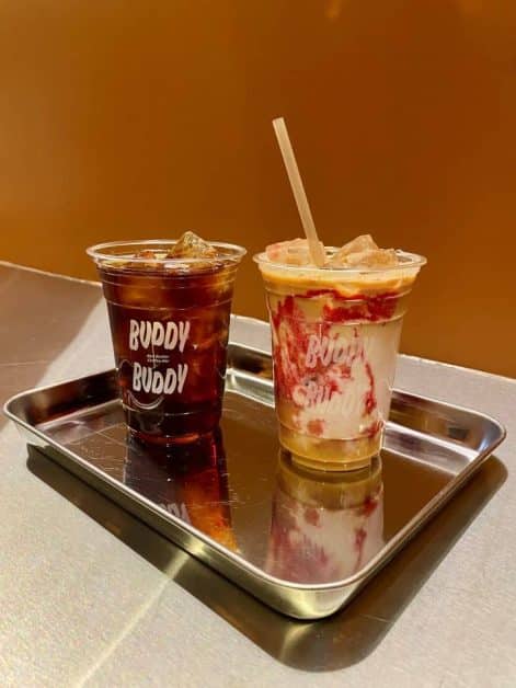 The iced peanut butter and raspberry jam latte from Buddy Buddy coffee shop in New York City served on a silver metal tray.
