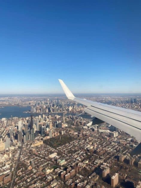 View of NYC skyline from an airplane window, approaching LaGuardia Airport for landing.