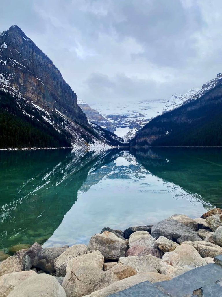The reflections of the mountains and Victoria Glacier onto the calm waters of Lake Louise in the early morning in Banff National Park.