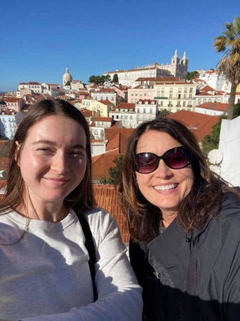 My mom and I standing at the Miradouro de Santa Luzia viewpoint in Alfama overlooking the red orange colored roofs and the river.