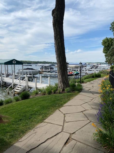 Stone shore path lined with flowers leading past docked boats on Lake Geneva, Wisconsin.