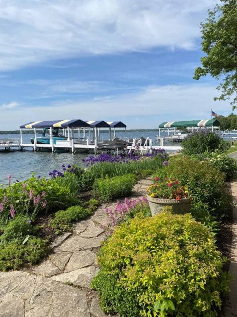 Stone path through a flower garden with irises leading to covered boat docks on Lake Geneva, Wisconsin.